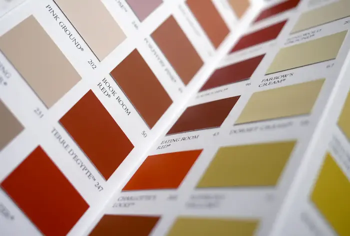 Un nuancier de peinture avec différentes teintes de couleurs, incluant des tons de beige, rouge, marron et jaune, chacune étiquetée avec des noms comme 'Pink Ground', 'Book Room Red', 'Terre d'Égypte', 'Eating Room Red', et 'Farrow's Cream'.